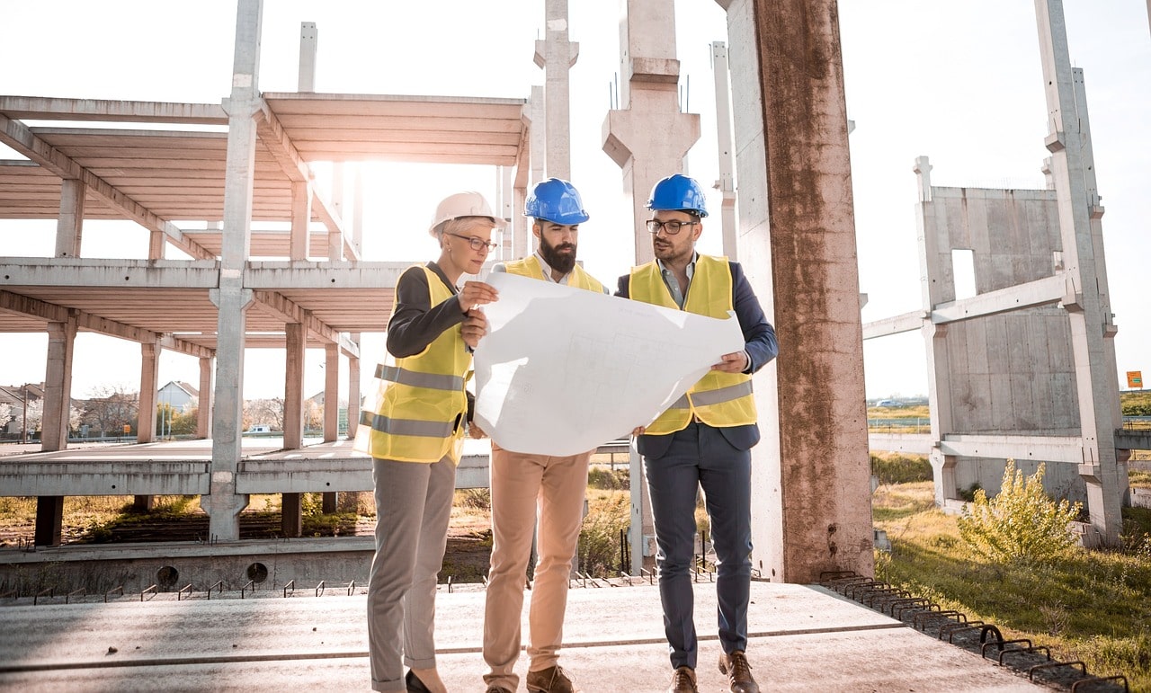 Three architecturers are discussing about a structure of building and one logo pasban builders